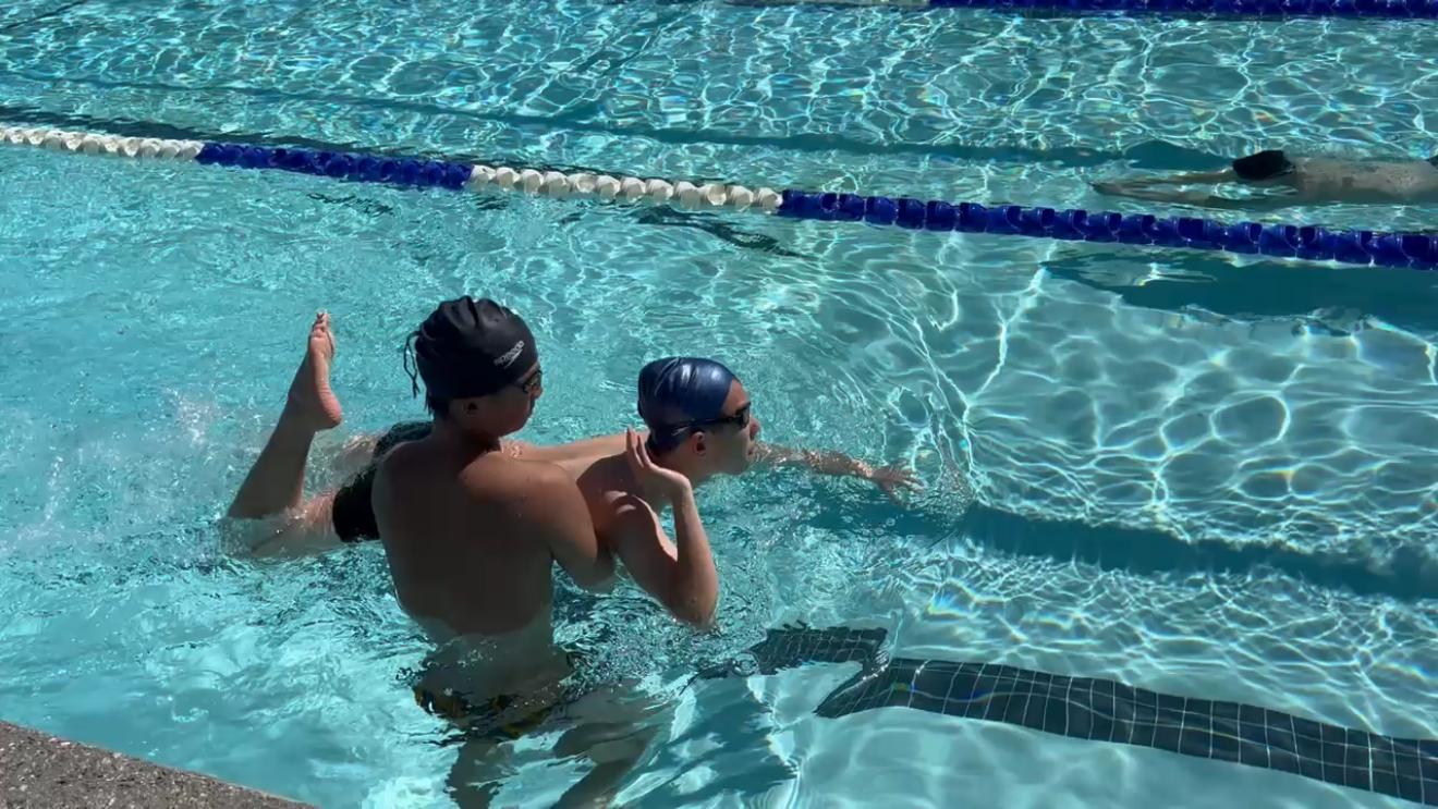 A Float coach supporting a young swimmer during a lesson